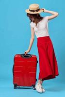 mujer sentado en un rojo maleta viaje estilo de vida vuelo azul antecedentes foto