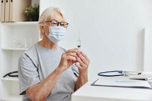 elderly woman in a medical mask holding a syringe in her hands treatment hospital photo