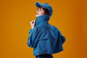 Beautiful fashionable girl in a cap and denim jacket posing studio model unaltered photo