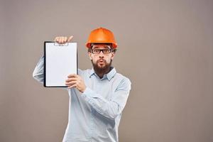 A man in a shirt with an orange hard hat engineer work documents rendering services photo