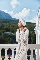 atractivo joven mujer en pie en el balcón mirando a el montañas vacaciones en el montañas en verano foto