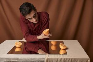 Man in shirt at table with mirror reflection of oranges model photo