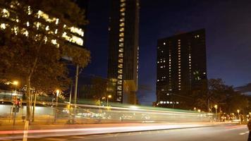 A timelapse at a street corner in barcelona at night with the traffic rushing past and skyscrapers in the background video