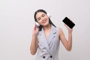 un joven mujer vistiendo auriculares disfrutando con música en blanco antecedentes foto