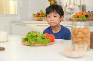 Asian boy feeling bored , unhappy to eat vegetables , health care concept photo