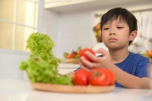 Asian boy feeling bored , unhappy to eat vegetables , health care concept photo