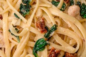 Delicious pasta with spinach, sun dried tomatoes, cheese, onions photo