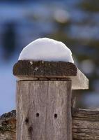 A snow cap on top of a wooden fence photo