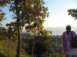 A woman standing on the edge of a hill looking forward to the Bay of Bengal photo