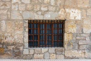 wooden window with iron grille in stone wall photo