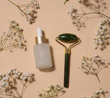 A glass white bottle with a dropper on a on beige background, a container for cosmetic products photo