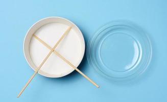 Open empty noodle bowl with and pair of wooden sticks on blue background, top view photo