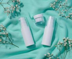 White plastic bottle and jar for cosmetics and sprigs of white gypsophila flowers, top view photo