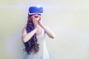 Smile young woman wearing using virtual reality VR glasses helmet headset on white background. Smartphone using with virtual reality goggles. Technology, simulation, hi-tech, videogame concept. photo