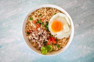 instant noodles cooking tasty eating with bowl - noodle soup, noodles bowl with boiled egg minced pork vegetable spring onion lemon lime lettuce celery and chili on table food photo