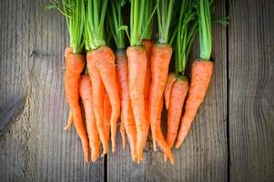 zanahoria en el fondo de la mesa, zanahorias frescas y dulces para cocinar frutas y verduras para el concepto de salud, manojo de zanahorias para bebés y hojas foto