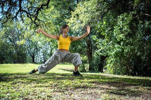 Profile of a woman practicing tai chi surrounded by trees. photo