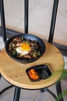 Rice topped with beef and egg on a wooden table in a restaurant photo