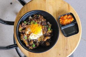 Rice topped with beef and egg on a wooden table in a restaurant photo