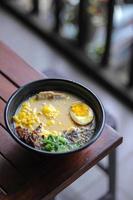 Bowl of miso soup with pork and egg on wooden table photo