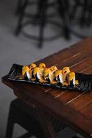 Sushi rolls on a black plate on a wooden table in a restaurant photo