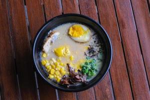 noodle soup with egg and vegetable in black bowl on wooden table photo