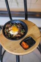 Rice topped with beef and egg on a wooden table in a restaurant photo