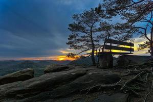 banco a un punto de vista en el bosque durante puesta de sol foto