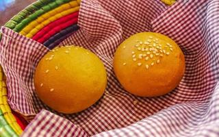 Delicious round buns with sesame seeds on wooden table Mexico. photo