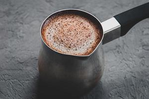 Black coffee brewed in cezve, closeup photo