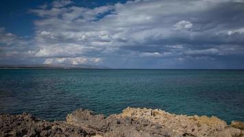 a pebble beach and Mediterranean sea with the Aeolian islands in the distance in Sicily, Italy. video