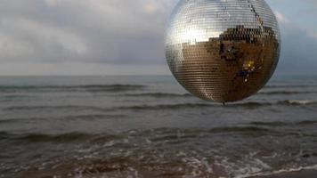 A spinning discoball on the beach with passing clouds video