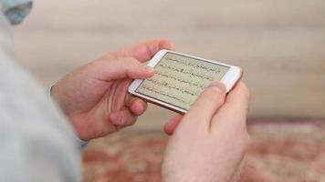 coran ouvert sur le écran de le téléphone il est holding, le alphabet de le religieux livre de Islam est arabe, le saint livre video