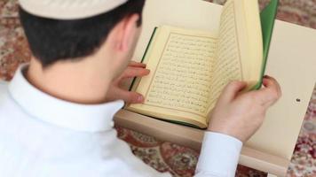 une homme qui mettre le coran dans le sien main sur le table et ouvert il, une Jeune homme séance dans une mosquée en train de lire le coran video