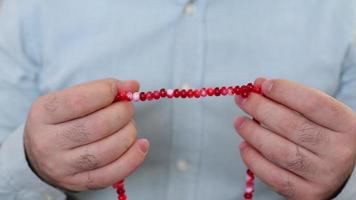 The rosary in the hand of a muslim man in a blue shirt, one by one man finishes the rosary that he worships with his fingers video