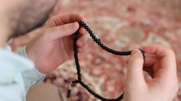un musulmán hombre participación un rosario para culto, musulmanes orar con un negro rosario y recuerda Alá, cree en uno Dios video