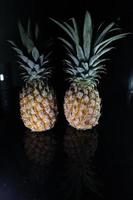 Pineapple fruit isolated on black background with reflection in its shadow. photo