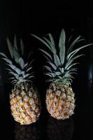 Pineapple fruit isolated on black background with reflection in its shadow. photo