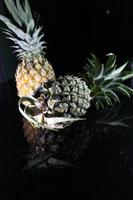 Pineapple fruit isolated on black background with reflection in its shadow. photo