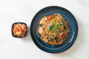 japchae or stir-fried Korean vermicelli noodles with vegetables and pork topped with white sesame photo