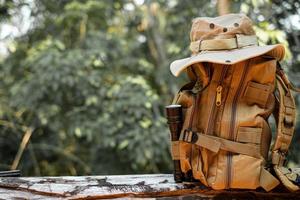 Bucket Hat and backpack hiking with a flashlight resting on wooden timber in the background is a forest photo