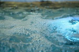 Blurred water background. Backlit water jet in the fountain. photo