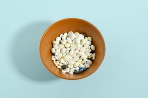 Plate with medicines on a blue background. Too many pills. Medicine theme blue background. photo