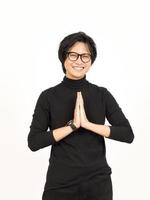 sonriente y haciendo namaste saludo de hermoso asiático hombre aislado en blanco antecedentes foto