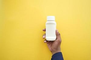 holding a Mayonnaise in container on yellow background photo