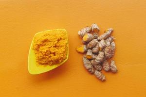 turmeric root and paste in a bowl on orange background photo