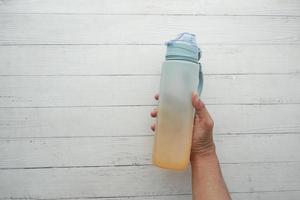 hand holding sport bottle on white wooden table photo