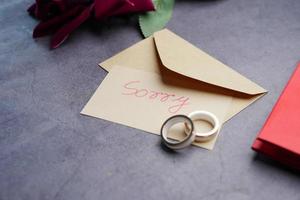 Note with the sorry word next to a wedding ring. photo