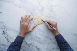 high angle view of hand drawing question mark on paper on office desk photo