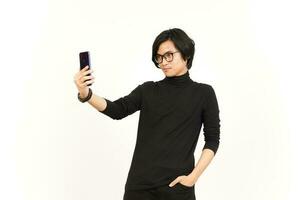 Take a Selfie using Smartphone Of Handsome Asian Man Isolated On White Background photo